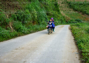 Une Maman transporte ses enfants sur un scooter sur la route du village de Pa lan Than, un village du nord du Vietnam dans le district de Mu cang Chai